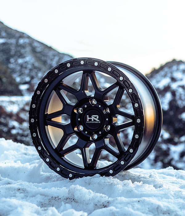 matte black hardrock offroad h105 on snowy surface with snow covered mountain range behind it