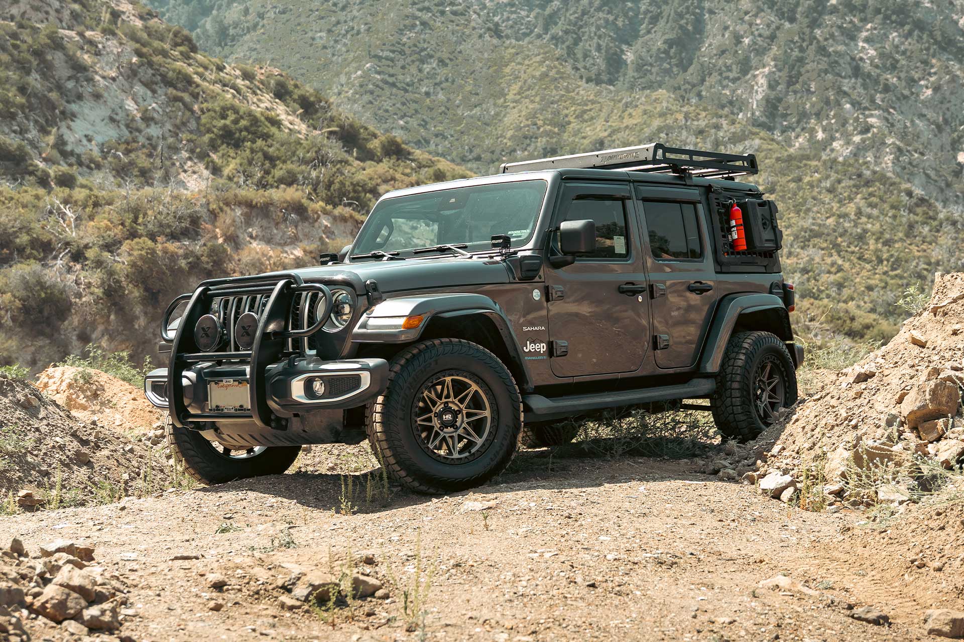 gray jeep wrangler sahara 4xe with matte bronze hardrock h109 off road wheels on sand