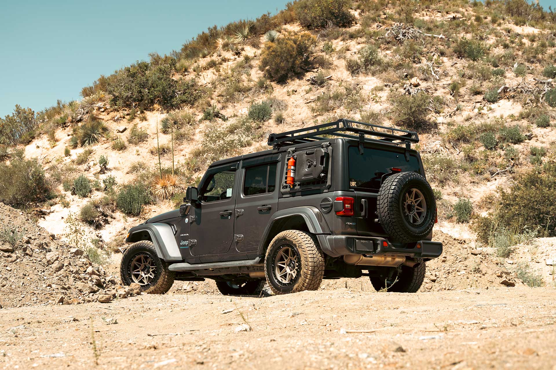 gray jeep wrangler sahara 4xe with matte bronze hardrock h109 off road wheels on sand