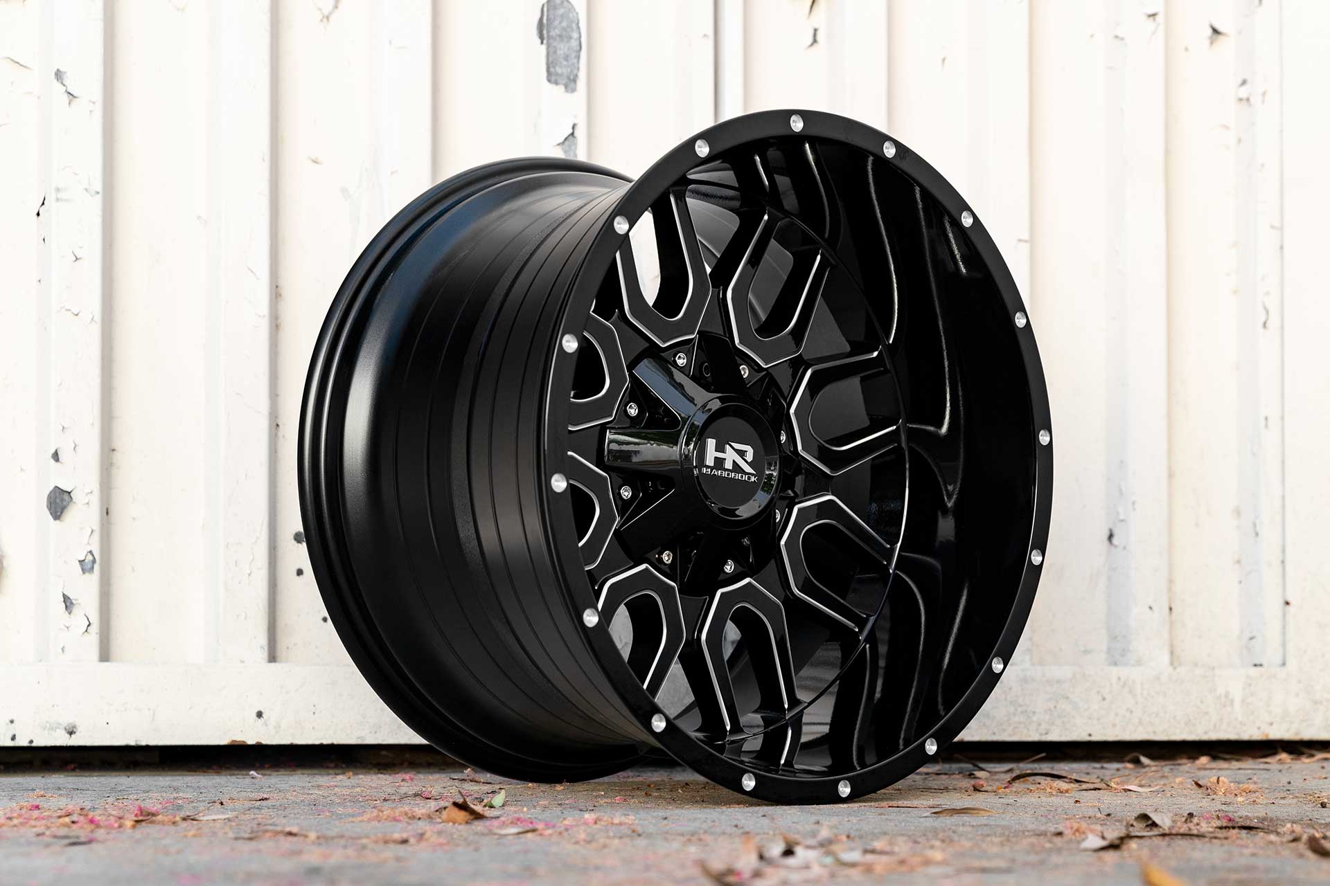 gloss black machined hardrock offroad h709 on ground next to freight container