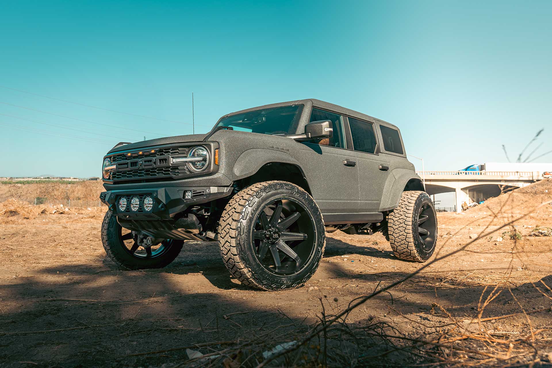 liner sprayed ford bronco bronco raptor with satin black hardrock offroad h502 truck wheels in an industrial scene with dirt and rocks